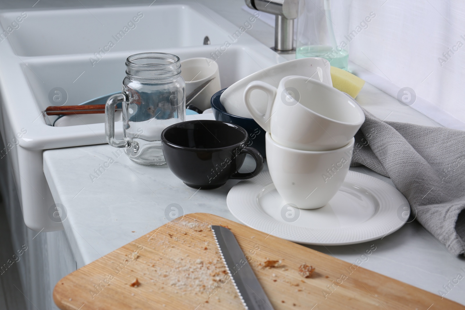 Photo of Many dirty utensils and dishware on countertop in messy kitchen