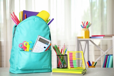 Bright backpack and school stationery on table indoors, space for text