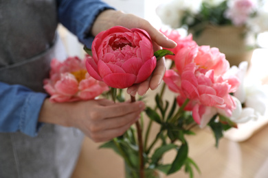 Florist making beautiful peony bouquet at table, closeup