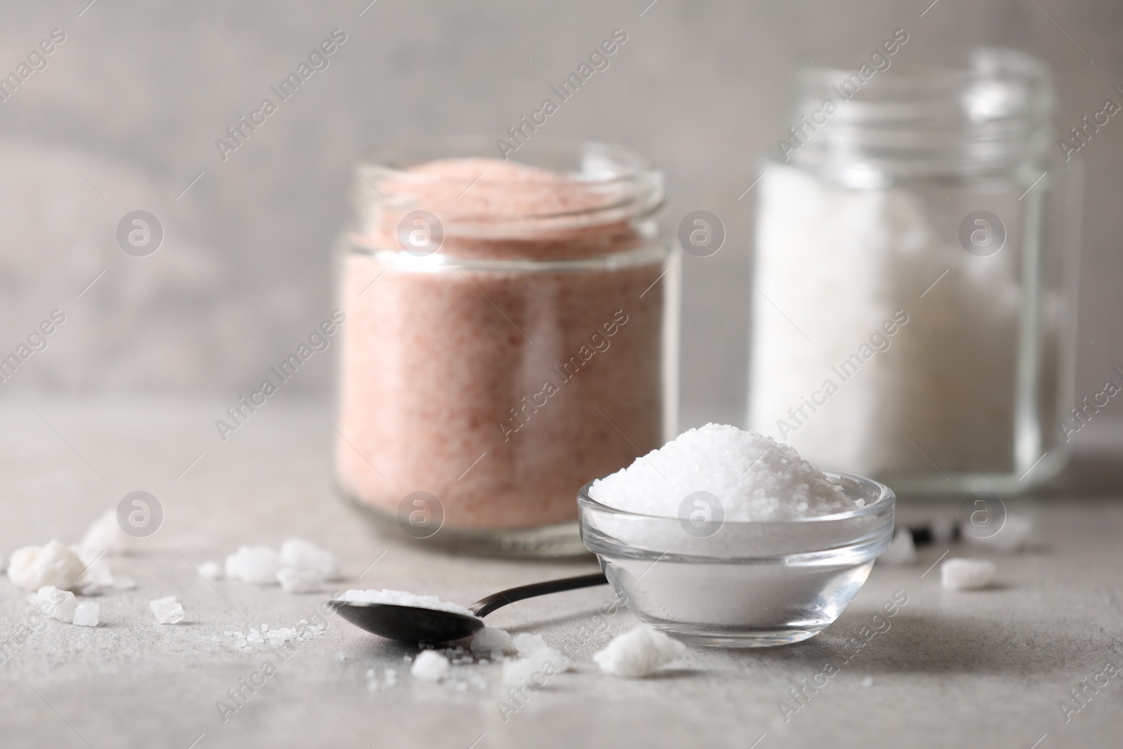 Photo of Different natural salt on grey table, closeup