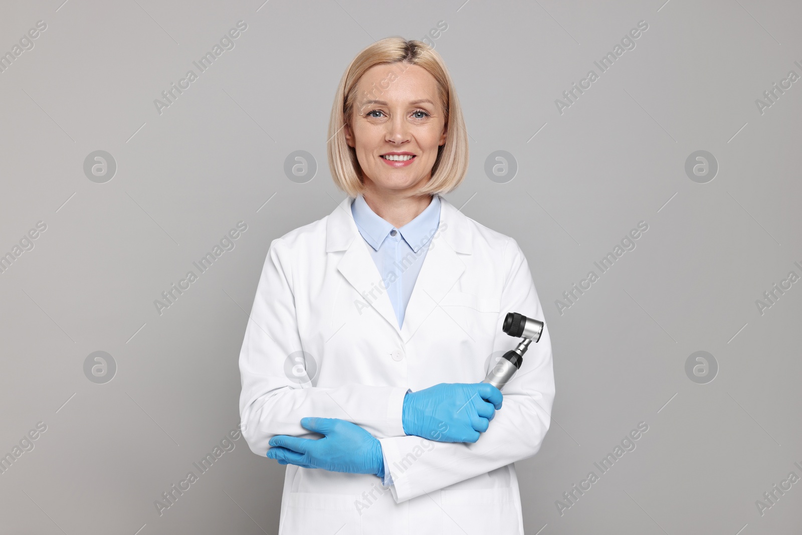 Photo of Happy dermatologist with dermatoscope on grey background