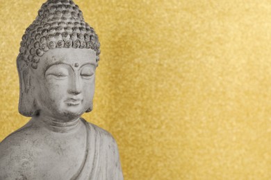 Photo of Buddha statue on golden background, closeup. Space for text