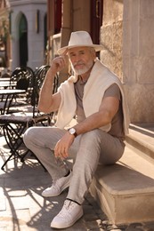Photo of Handsome senior man sitting on doorstep outdoors