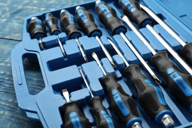 Photo of Set of screwdrivers in open toolbox on blue wooden table, closeup