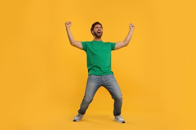 Photo of Emotional sports fan celebrating on orange background