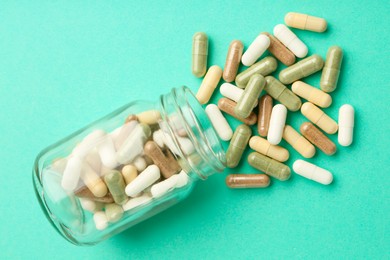 Photo of Vitamin pills and bottle on mint color background, top view