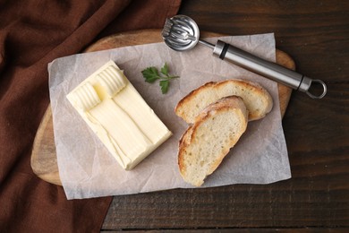 Tasty butter, slices of bread and spoon on wooden table, top view