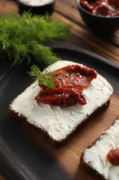 Delicious bruschetta with ricotta cheese, sun dried tomatoes and dill on wooden table, closeup