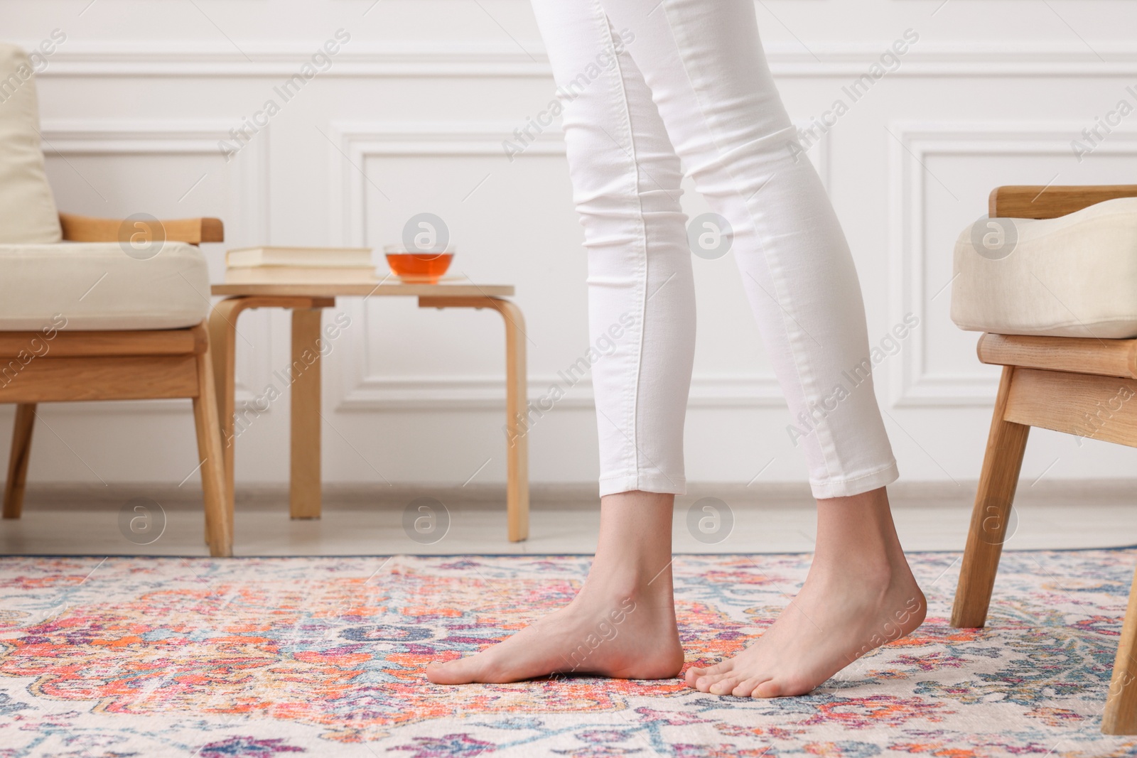 Photo of Woman standing on carpet with pattern at home, closeup. Space for text