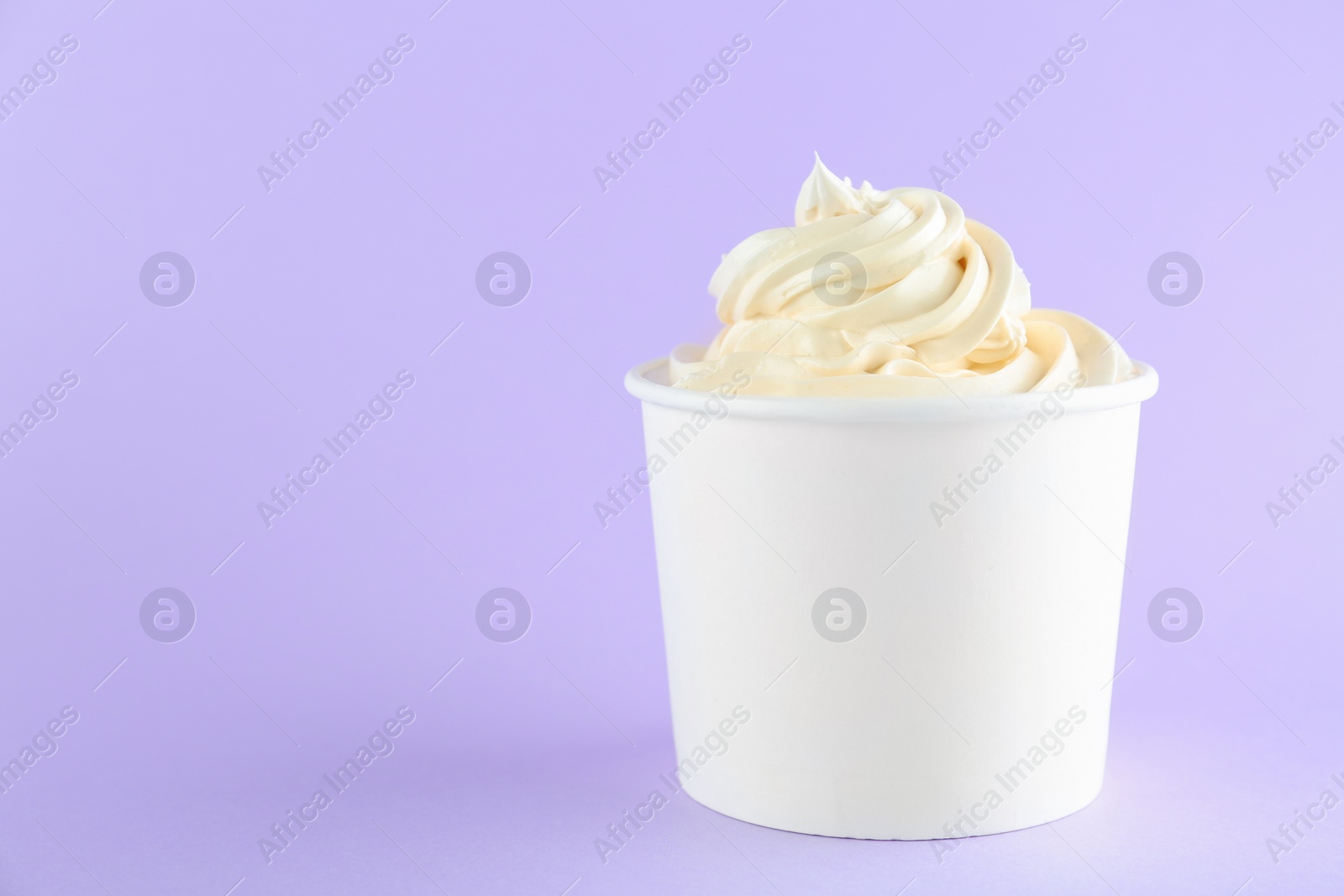 Photo of Cup with tasty frozen yogurt on violet background. Space for text