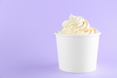 Cup with tasty frozen yogurt on violet background. Space for text