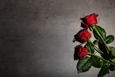 Photo of Beautiful red roses on grey background, top view. Funeral symbol