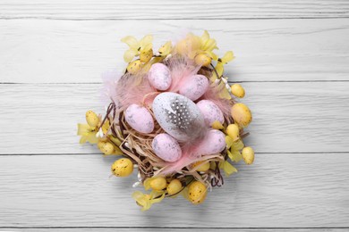 Photo of Festively decorated Easter eggs on white wooden table, top view