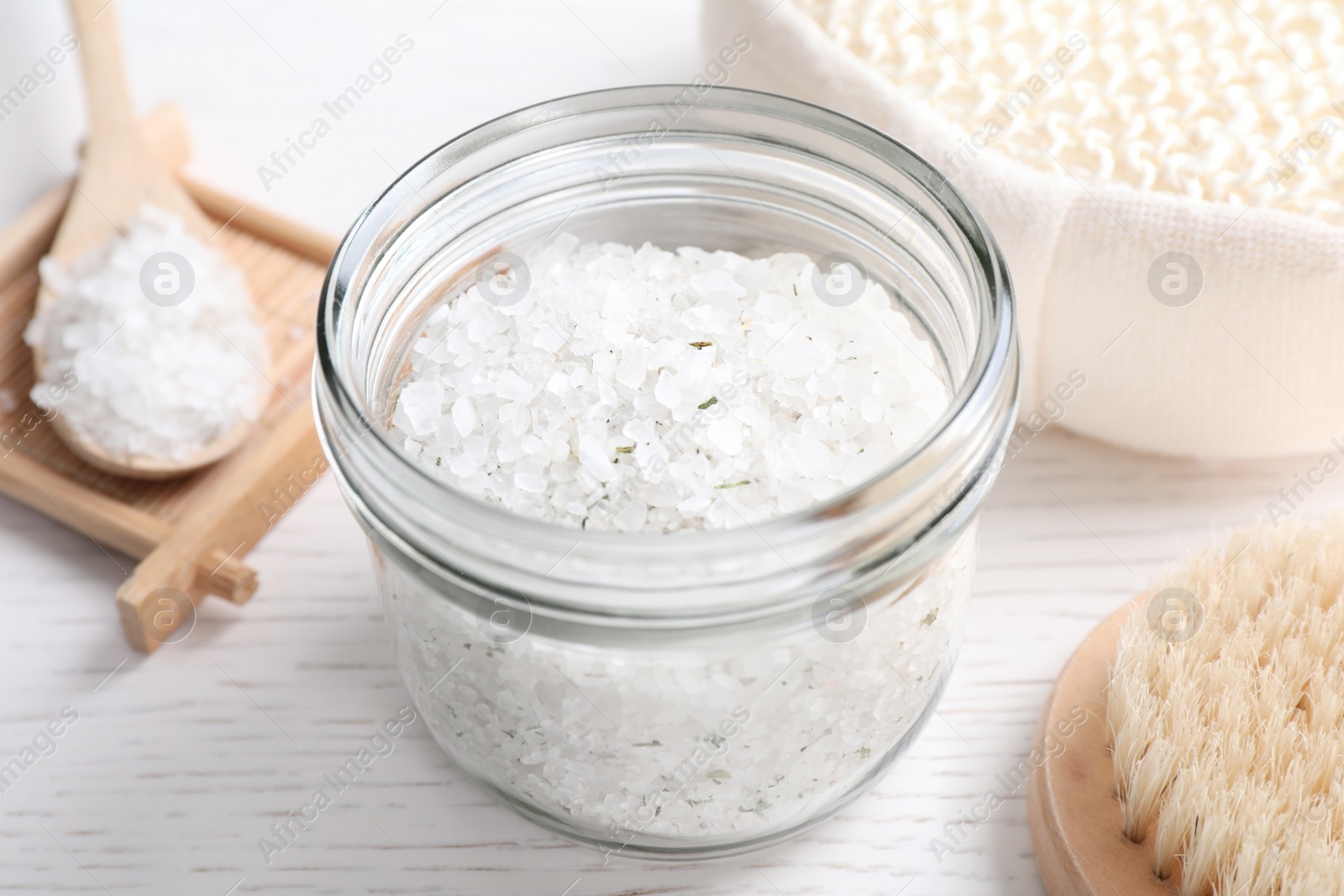 Photo of Sea salt for spa scrubbing procedure in jar on white wooden table