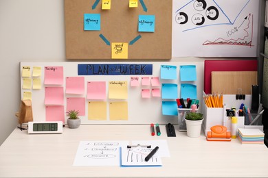Business process planning and optimization. Workplace with colorful paper notes and other stationery on white wooden table