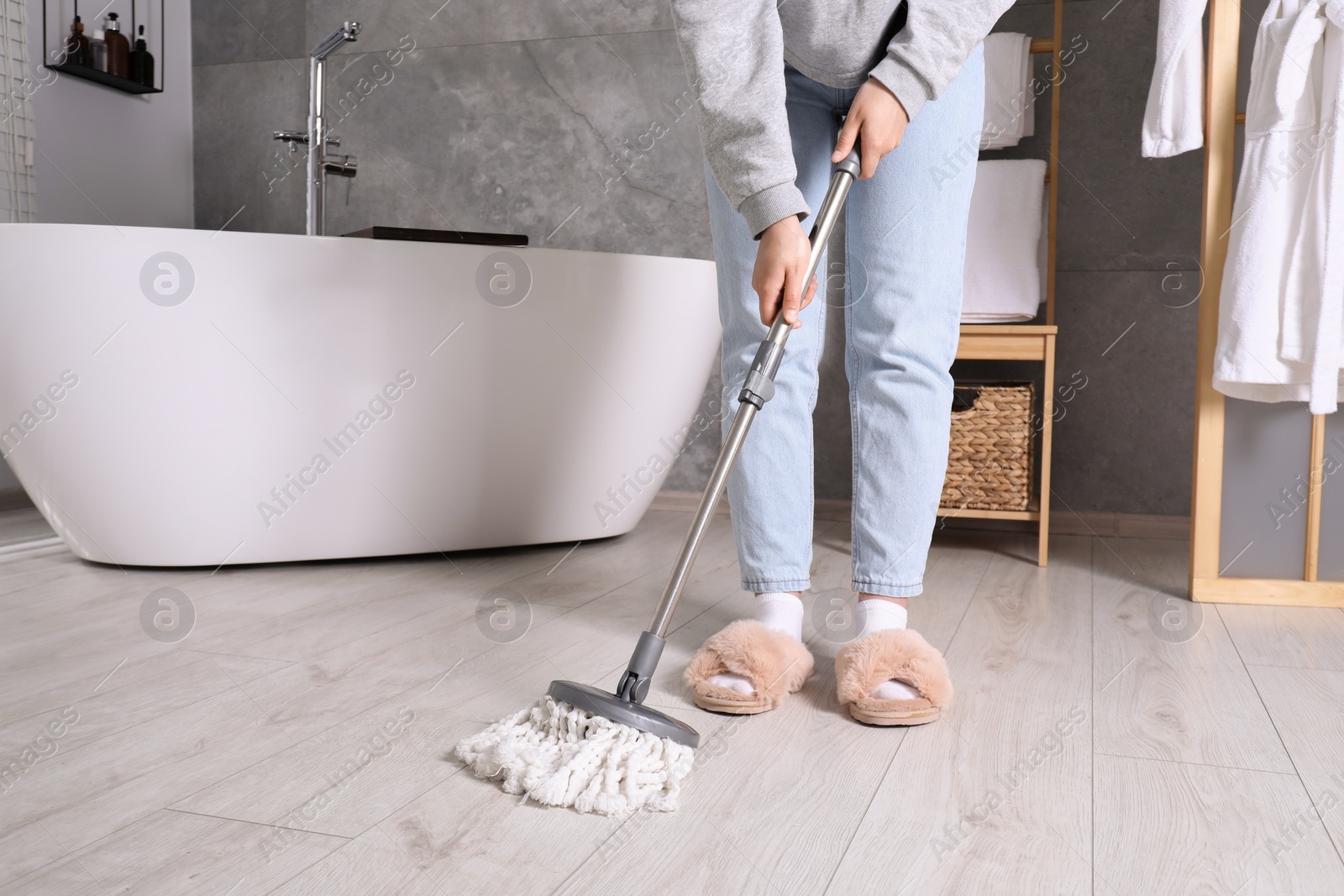 Photo of Woman cleaning parquet floor with mop in bathroom, closeup