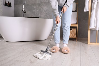 Woman cleaning parquet floor with mop in bathroom, closeup