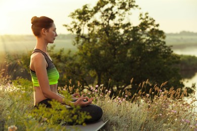 Photo of Woman meditating in meadow. Space for text