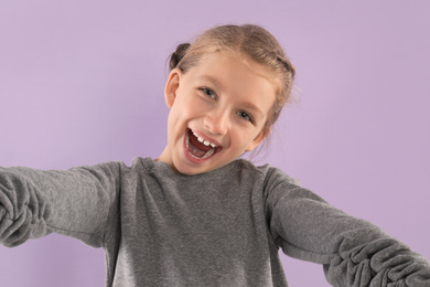 Photo of Excited little blogger recording video on violet background