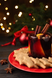 Photo of Aromatic mulled wine and cookies on wooden table, closeup
