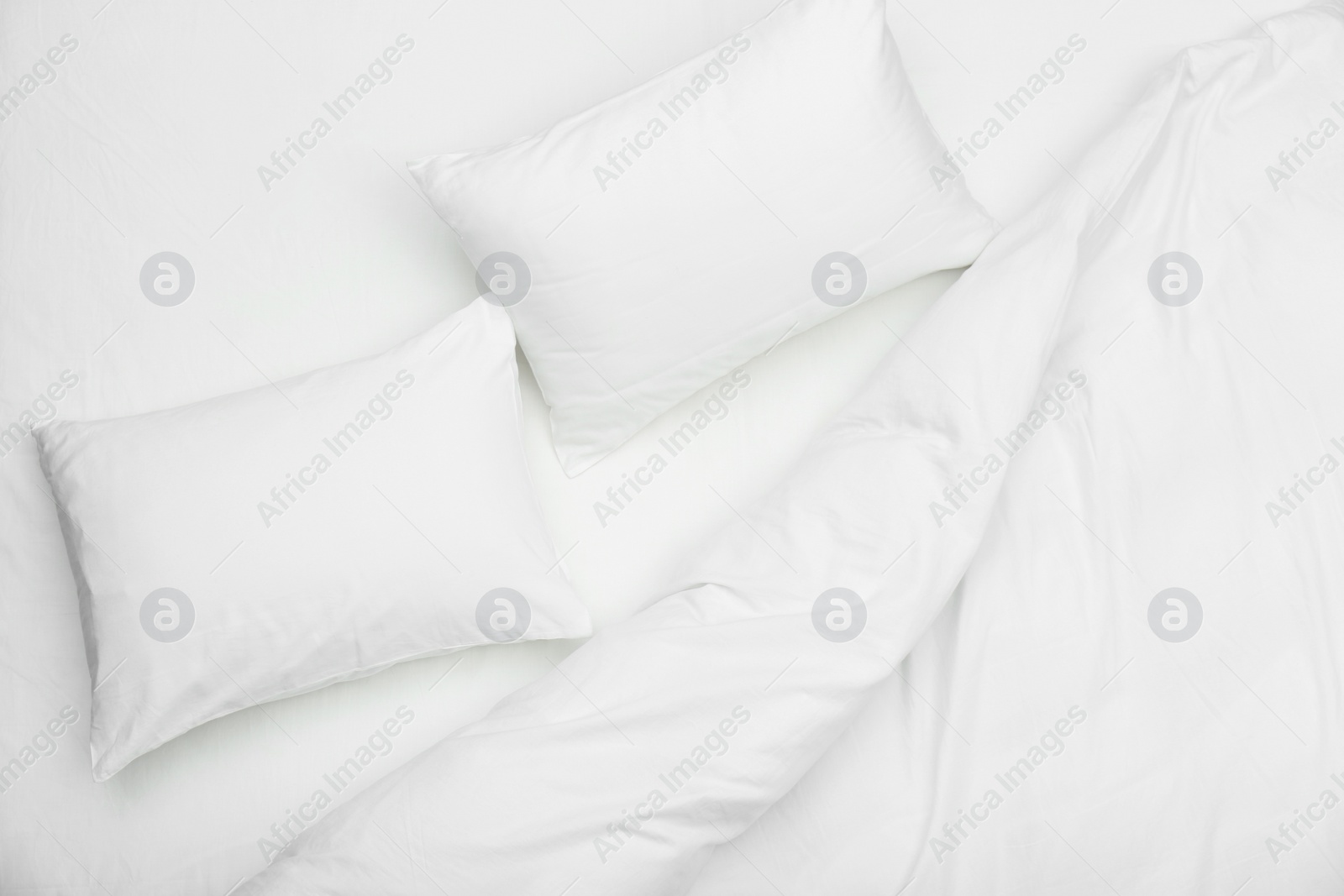 Photo of Soft white pillows and blanket on bed, top view