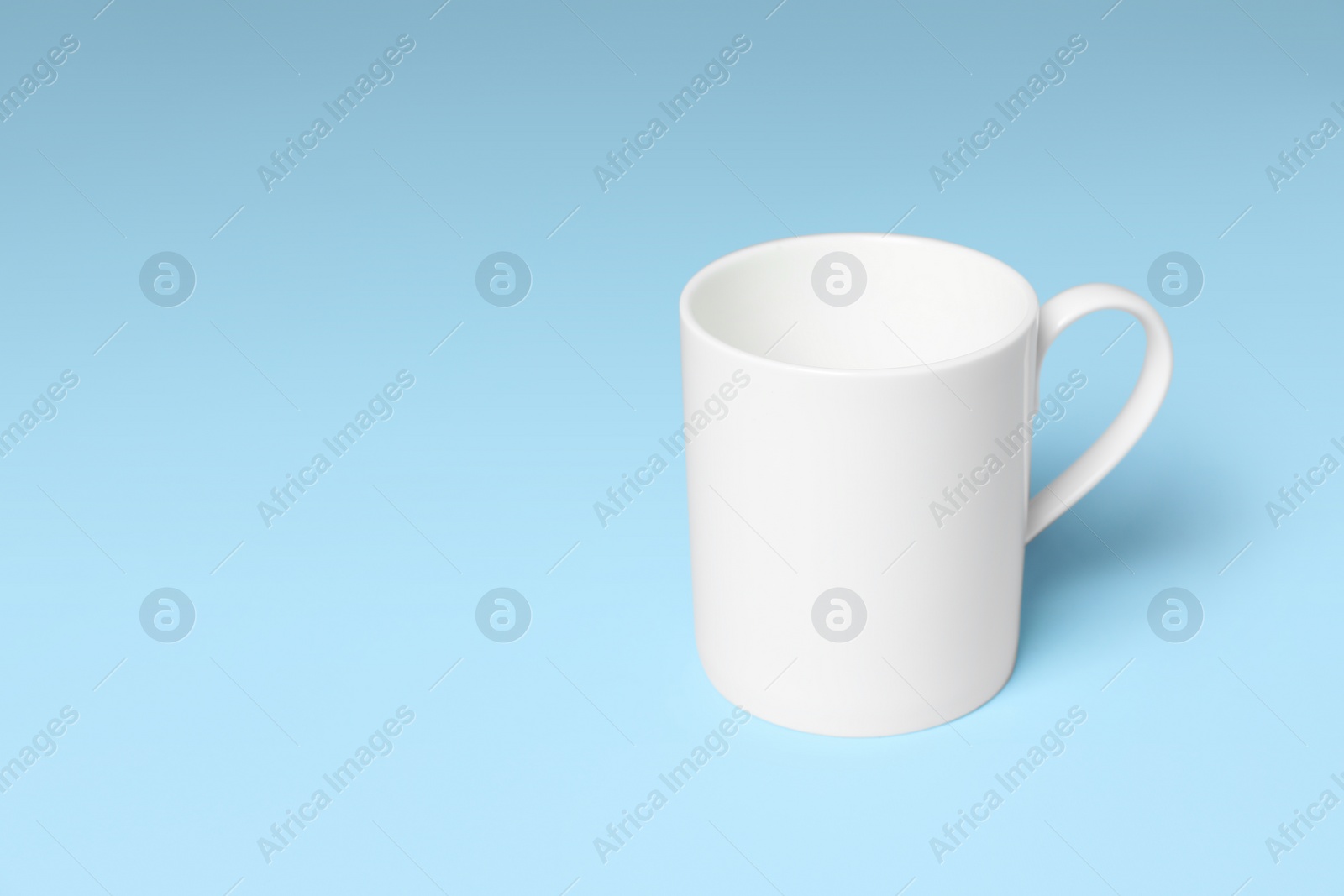 White ceramic mug on light blue background, space for text Photo of White ceramic mug on light blue background, space for text
