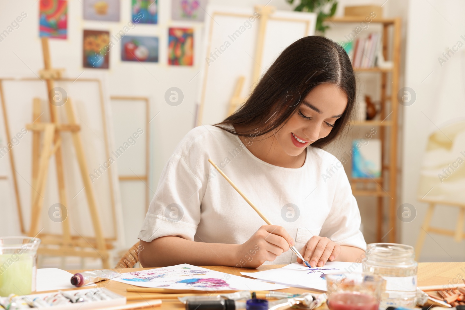 Photo of Beautiful young woman painting in studio. Creative hobby