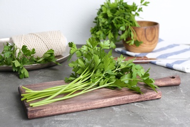 Wooden board with fresh green parsley on table