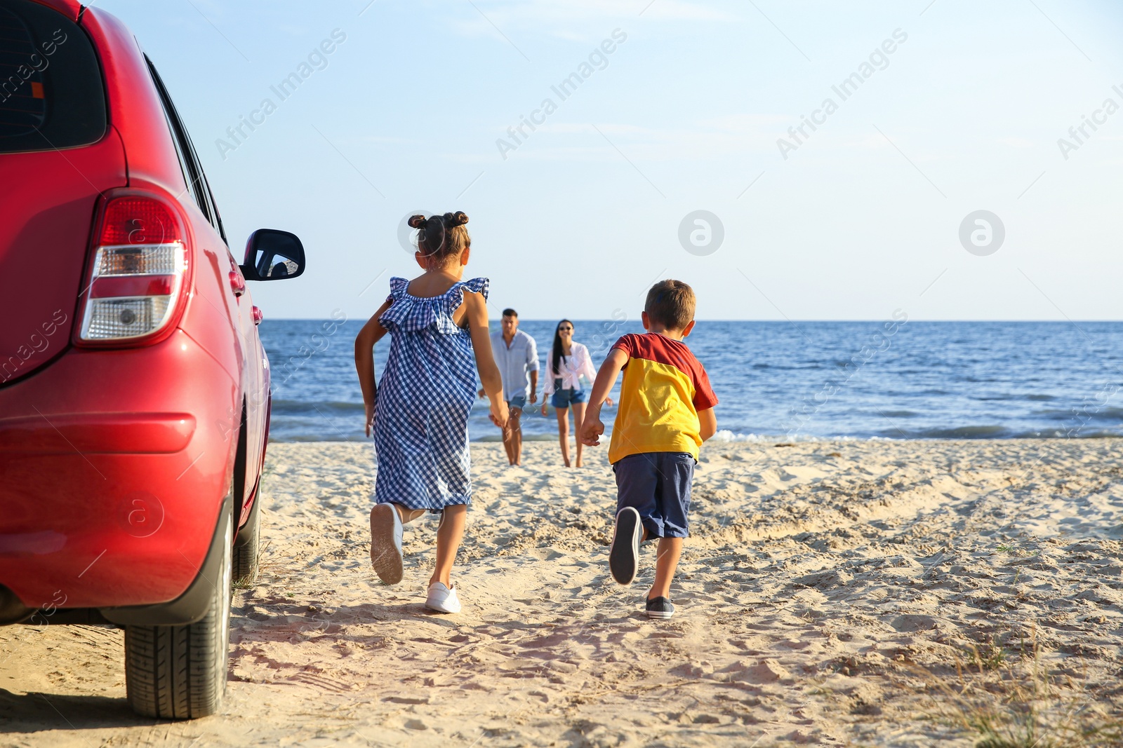 Photo of Little children running to their parents on sandy beach. Summer trip