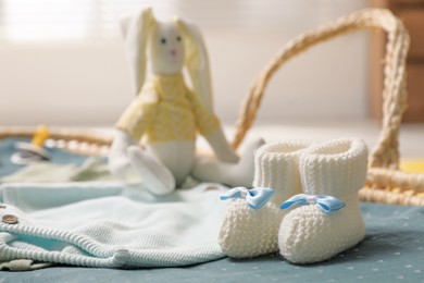 Photo of Baby booties and clothes in basket indoors, closeup. Space for text