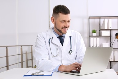 Photo of Pediatrician working on laptop at desk in office