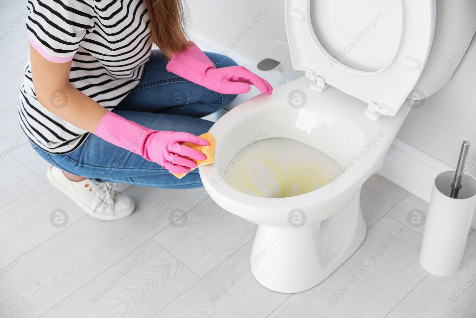 Photo of Woman cleaning toilet bowl in bathroom, closeup