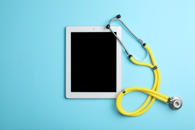 Stethoscope and tablet with space for text on color background, top view. Medical device