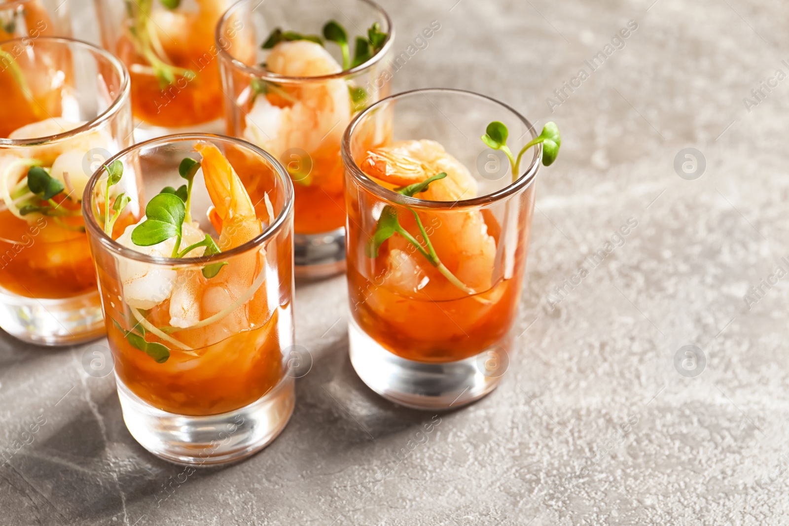 Photo of Delicious shrimp cocktail shots on grey table