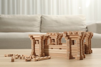 Photo of Wooden fortress and building blocks on table indoors. Children's toy