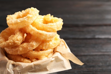 Dishware with homemade crunchy fried onion rings on wooden table, closeup