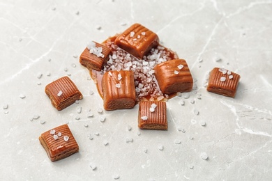 Photo of Delicious candies with salted caramel sauce on light background