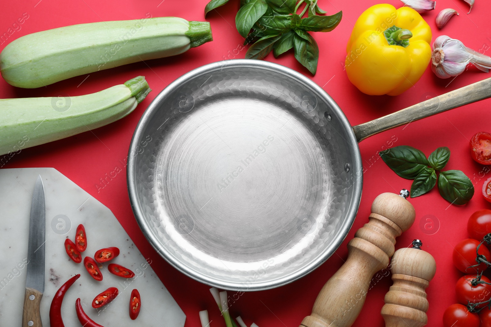 Photo of Flat lay composition with frying pan and fresh products on red background