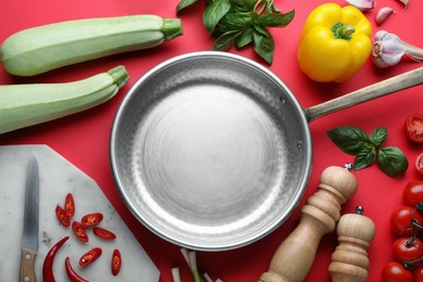 Flat lay composition with frying pan and fresh products on red background