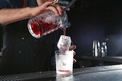 Photo of Barman making Red Russian cocktail at counter in pub, closeup. Space for text