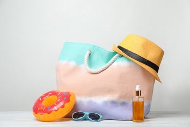 Photo of Bag with beach objects on table against light background