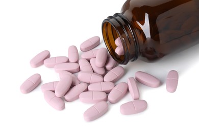 Photo of Scattered vitamin pills and bottle isolated on white
