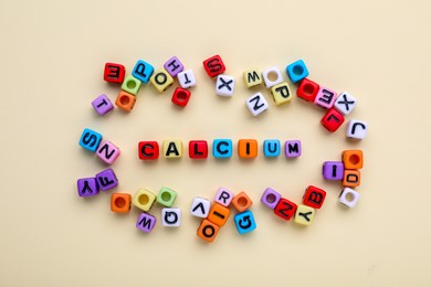 Photo of Word Calcium made of colorful plastic beads with letters on beige background, top view