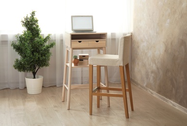 High wooden table with laptop as stand up workplace in modern interior