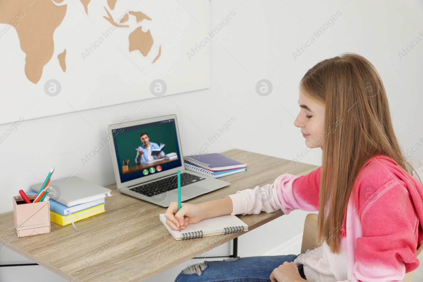 Image of Distance learning, online school lesson. Girl studying at home during quarantine and lockdown due to Covid-19 pandemic