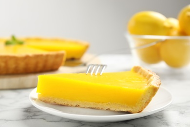 Photo of Slice of delicious homemade lemon pie on white marble table