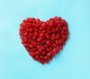 Photo of Heart shaped heap of sweet cherries on color background, top view. Dried fruit as healthy snack