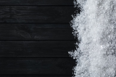 Photo of Snow and space for text on black wooden background, top view. Christmas time