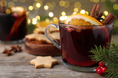 Photo of Aromatic mulled wine on wooden table, closeup. Space for text
