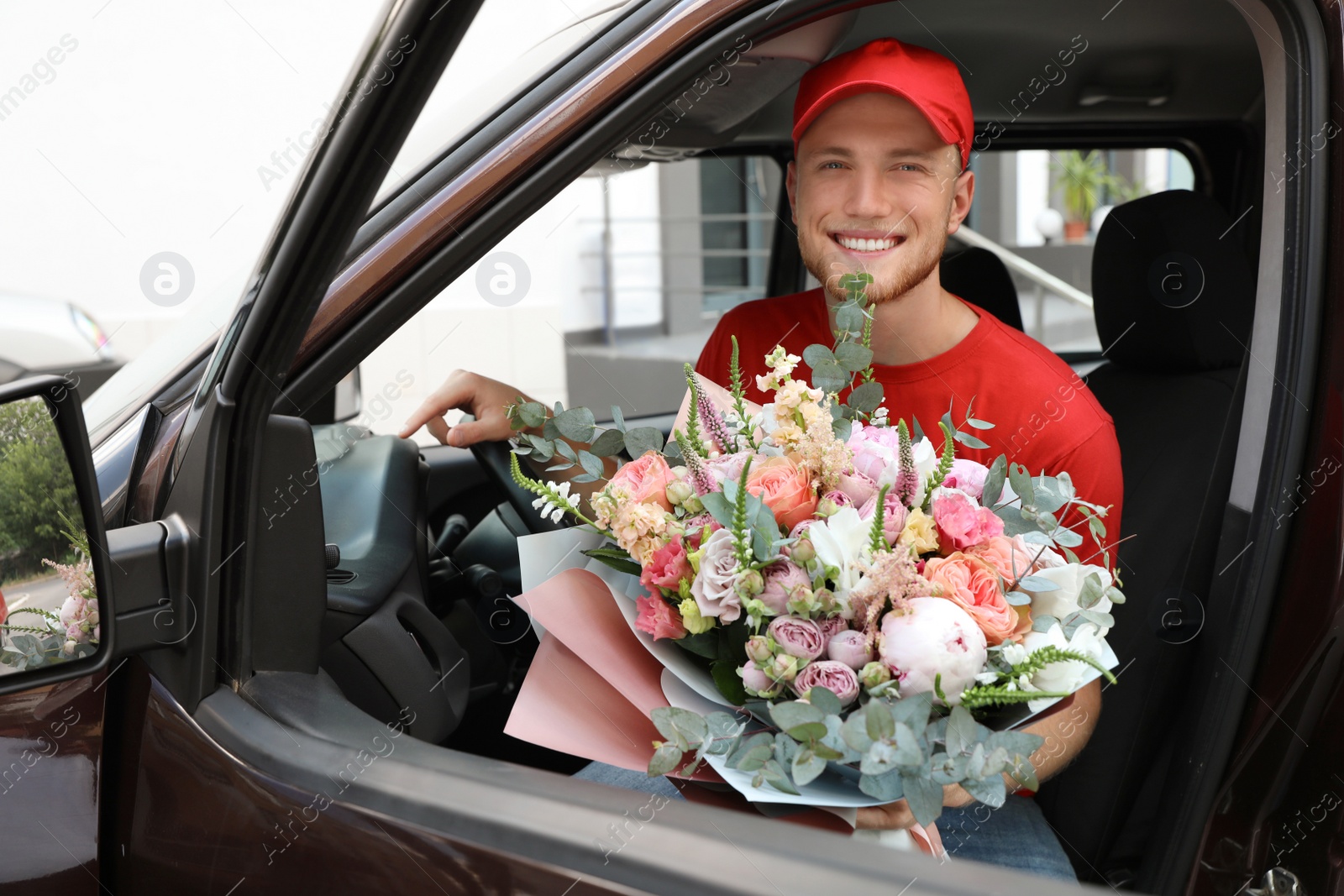 Photo of Delivery man with beautiful flower bouquet sitting in car